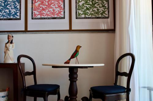 a toy bird sitting on a table with two chairs at Pousada a Capela in Arembepe