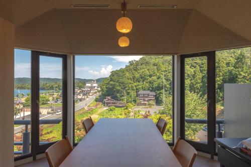 a dining room table with chairs and a large window at Hotel Kitanoya in Miyazu