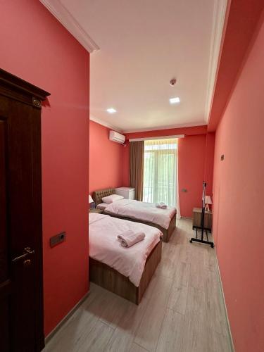 two beds in a room with red walls at Khidikari Hotel in Ambrolauri