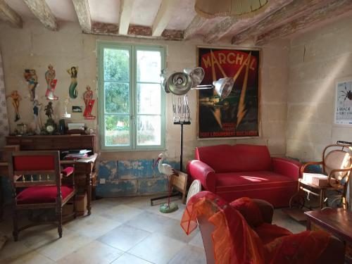 - un salon avec un canapé rouge et un piano dans l'établissement maison belle au bois dormant, à Rigny-Ussé