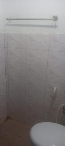 a bathroom with a white tiled wall and a toilet at Crown Majesty in Arugam Bay