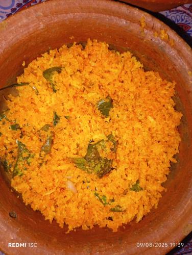 a wooden bowl filled with yellow rice with herbs at Villu Villa in Anuradhapura