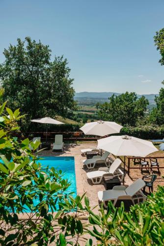 a swimming pool with umbrellas and chairs and a group ofitures at Al Podere del Nonno Romolo in Sansepolcro