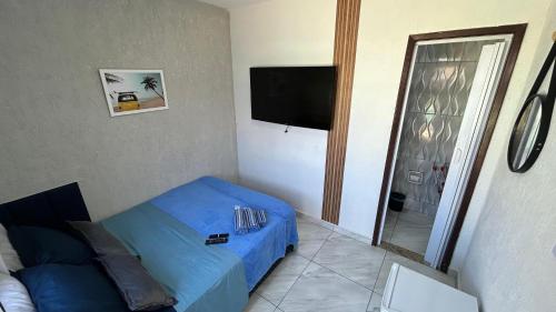 a bedroom with a blue bed and a flat screen tv at Pousada Aconchego de Maricá in Maricá