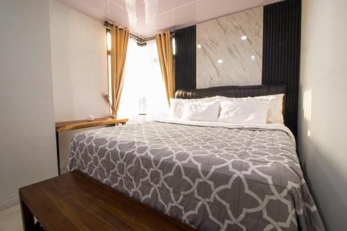 a bedroom with a bed with a gray comforter and a window at Sejahtera Apartment in Jogja 3bedrooms in Kejayan