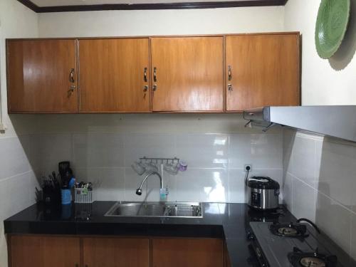 a kitchen with wooden cabinets and a sink at Sejahtera Apartment in Jogja 3bedrooms in Kejayan