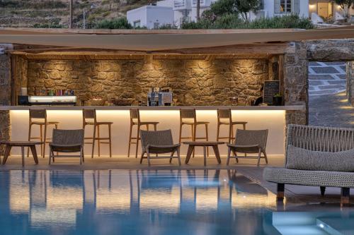 a bar at a hotel with chairs and a pool at Paolas Sunset in Agios Stefanos