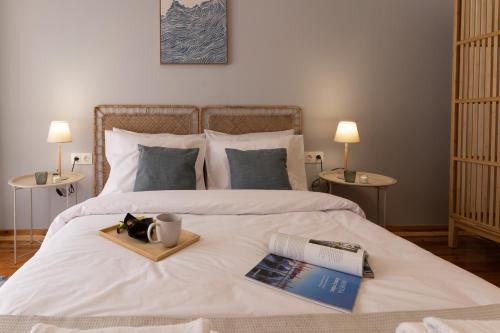 a bed with a tray with a book and a coffee mug at Aristoteluos By the Sea in Thessaloniki
