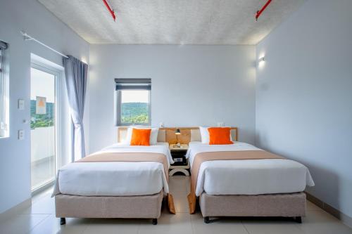 a room with three beds with orange pillows at The Up Hotel Phu Quoc Island - The Poolside Escape in Phu Quoc