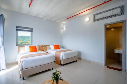 a white room with two beds and a bathroom at The Up Hotel Phu Quoc Island - The Poolside Escape in Phu Quoc