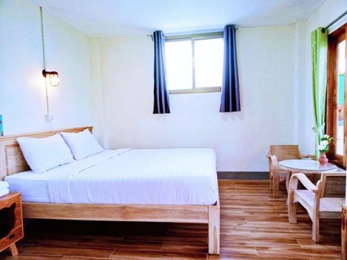 a bedroom with a bed and a table and a window at Kiangna resort Chiang Rai in Ban Pa O (1)
