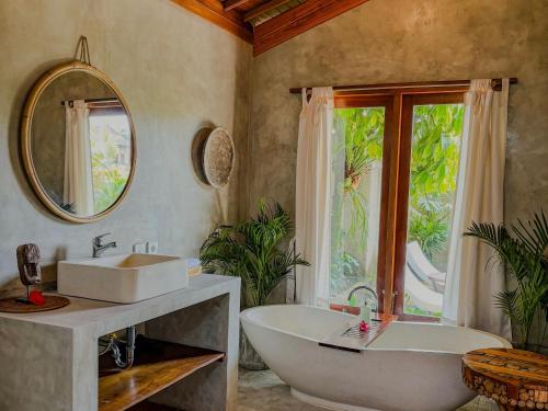 une salle de bain avec une baignoire, un lavabo et un miroir dans l'établissement Uma Phala Villa, à Ubud