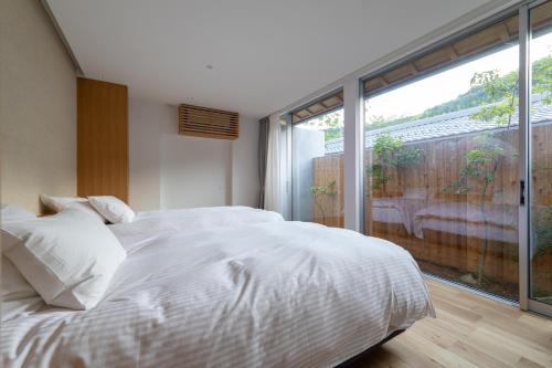 a bedroom with a white bed and a large window at Villa NIGIN in Miyazu