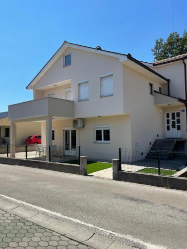 a white building with a car parked in front of it at Elbas Apartman in Široki Brijeg