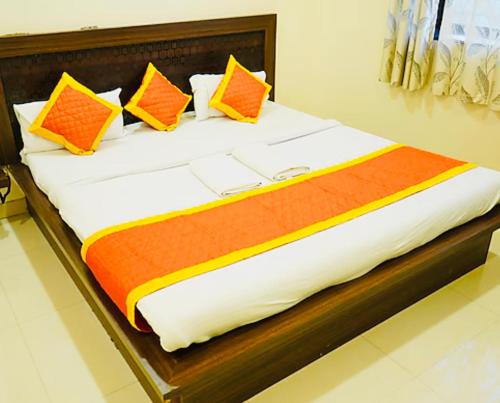 a bed with orange and yellow pillows on it at RADHIKA INn in Khātu