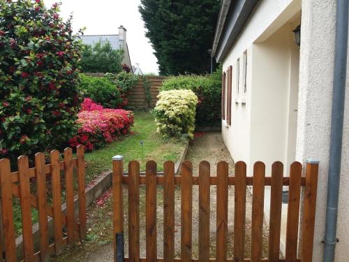 a wooden fence in front of a house with flowers at Maison trois chambres en impasse in Saint-Martin-des-Champs