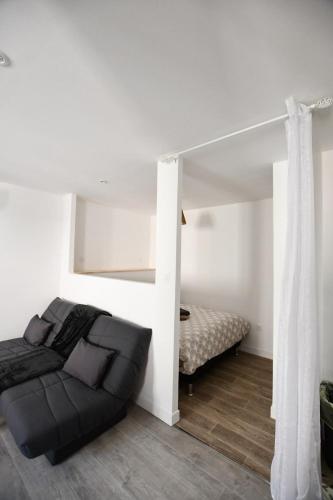 a bedroom with a black couch and a bed at Le Petit Cocon in Château-Chinon