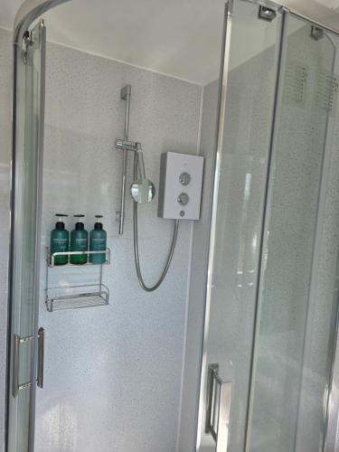 baño con ducha y 2 botellas azules en Chalet 80, en Sandown