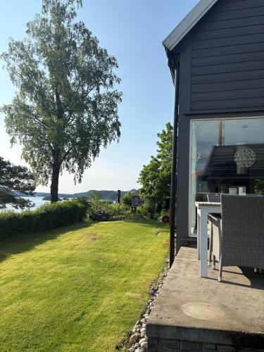 a house with a patio with a grill and a lawn at Charming Seaside Home with Fjord Views in Asker