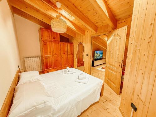 a bedroom with a white bed in a wooden room at Alloggio Stella Alpina in Sondalo