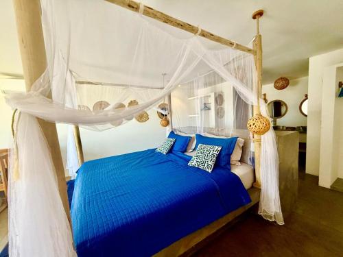 a bedroom with a blue bed with a canopy at Villa Beleza Prea Beachfront private room in Prea