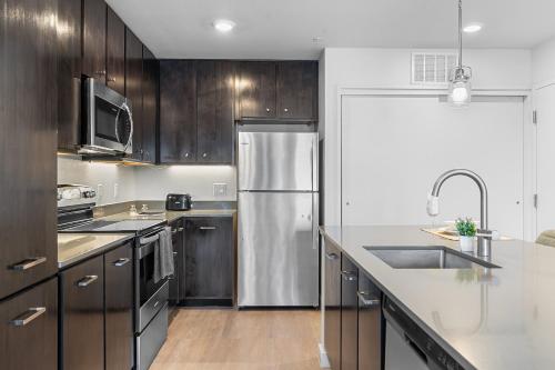 a kitchen with wooden cabinets and a stainless steel refrigerator at Luxury Home W Pool & Gym Mins To Baylor Hospital in Marble Falls