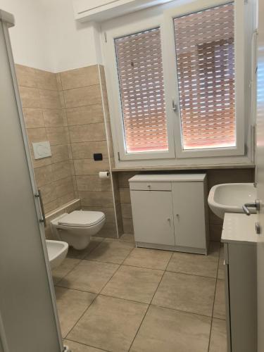 a bathroom with a toilet and a sink and two windows at Sony Affittacamere in Desenzano del Garda