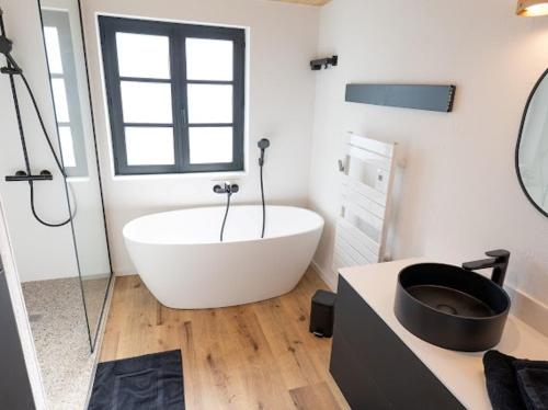 a bathroom with a large white tub and a sink at Ferme PFRIMMER in Breuschwickersheim