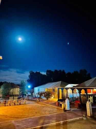 a group of tables and a building at night at Merzouga Desert Experience Camp-Erg Chebbi Sunset & Camel Ride in Merzouga