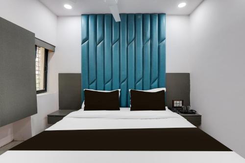 a bedroom with a large bed with a blue headboard at Hotel O New A1 in Ahmedabad