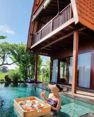 a woman sitting in a pool next to a house at Bhumi Lovina Residence & Villa in Singaraja