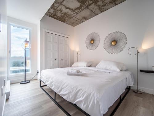 ein weißes Schlafzimmer mit einem großen Bett und zwei Spiegeln in der Unterkunft Caïman 806 in Québec