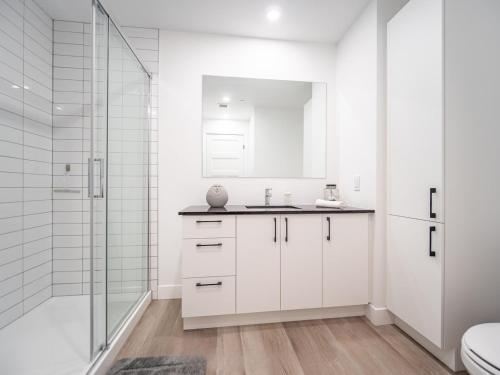 ein weißes Badezimmer mit Waschbecken und Dusche in der Unterkunft Caïman 806 in Québec