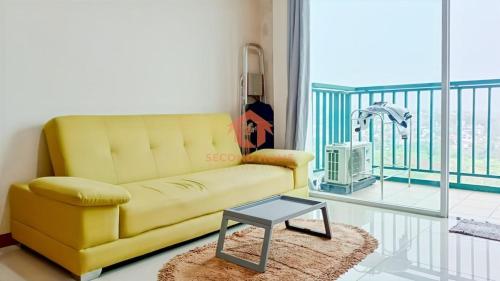 a living room with a yellow couch and a table at Marbella 2BR Apt Pool & Wi-Fi in Bandung