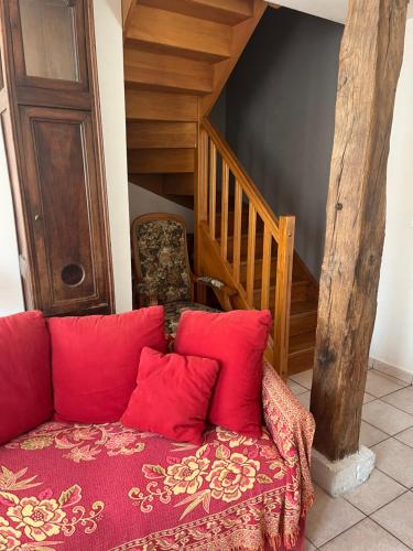 a couch with red pillows sitting next to a staircase at Une maisonnette au cœur de la Sologne des étangs in La Ferté-Beauharnais