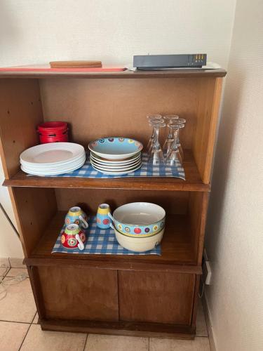 a wooden shelf with plates and dishes on it at Une maisonnette au cœur de la Sologne des étangs in La Ferté-Beauharnais