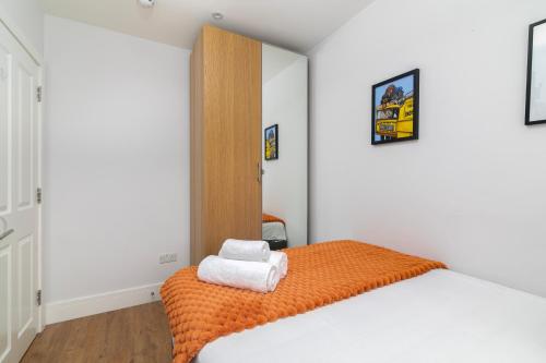 a bedroom with a bed with an orange blanket at Stylish Camden Town Apartments in London