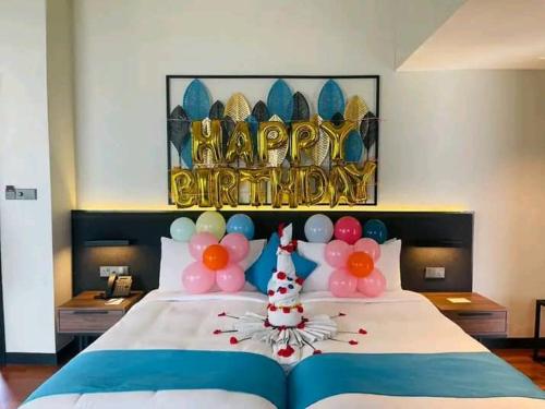 a bed with balloons and a happy birthday sign on it at Avani Sepang Goldcoast Resort in Tanjong Sepat