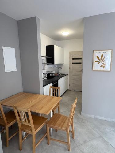 a kitchen and dining room with a wooden table and chairs at Apartamenty Na Fali in Kołobrzeg