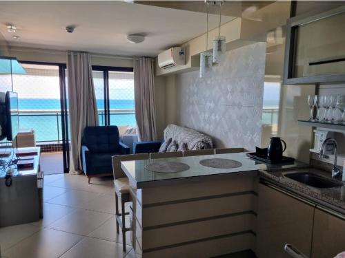 a kitchen with a counter top and a living room at Apartamento de Luxo Landscape Beira Mar Platinum in Fortaleza
