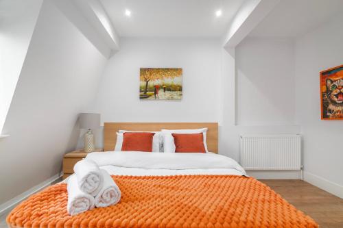 a bedroom with a large bed with orange sheets at Stylish Camden Town Apartments in London