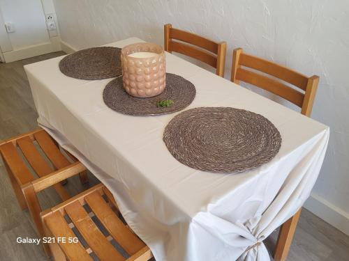 a table with two straw hats and a candle on it at Logement parents CAMP BASKET SUPERDEVOLUY in Le Dévoluy