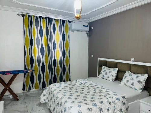a bedroom with a bed and a window with curtains at GodIsGood Residency in Yaoundé