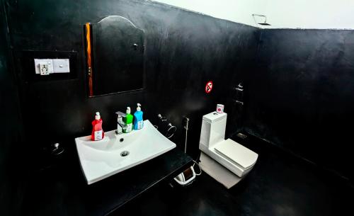 a black bathroom with a sink and a toilet at Su Casa Ella in Ella