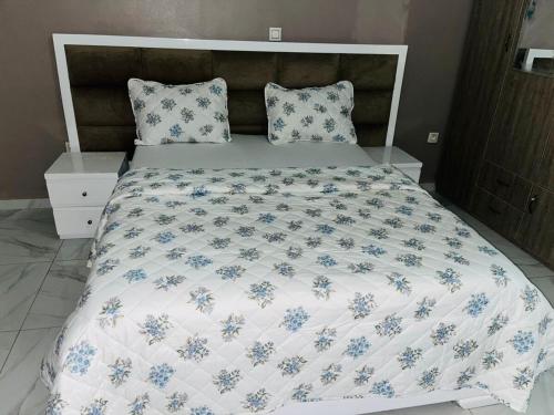 a bed with a white and blue comforter and pillows at GodIsGood Residency in Yaoundé