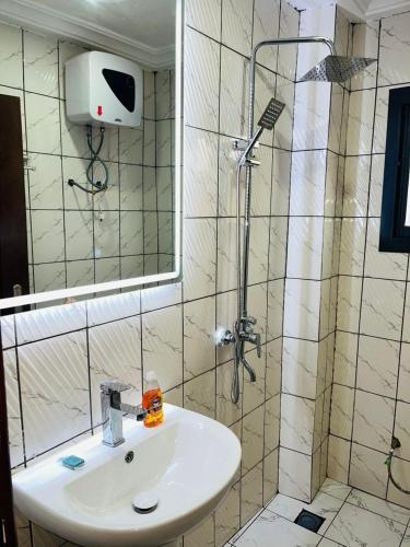 a bathroom with a shower and a white sink at GodIsGood Residency in Yaoundé