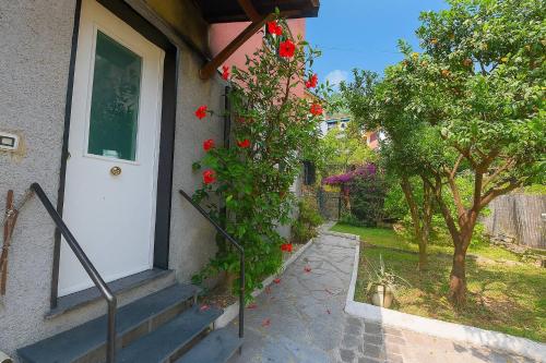 Una casa con una puerta blanca y un arbusto con rosas rojas. en Mulinetti, en Recco