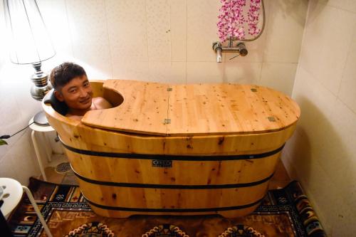 a boy sitting in a wooden tub in a bathroom at 33 Soksoom Centre for Well-Being & Happinesss - Boutique Hotel in Thimphu
