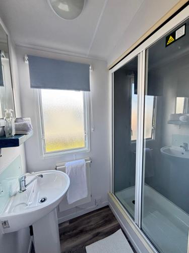 ein weißes Badezimmer mit Waschbecken und Dusche in der Unterkunft Family-Friendly 3-Bed Caravan Recently Renovated on Seven Bays Holiday Park, Padstow in Saint Merryn