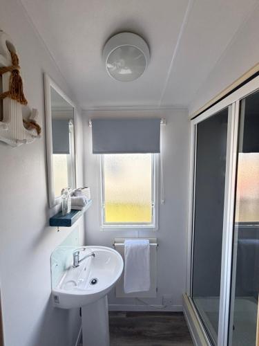 a white bathroom with a sink and a window at Family-Friendly 3-Bed Caravan Recently Renovated on Seven Bays Holiday Park, Padstow in Saint Merryn